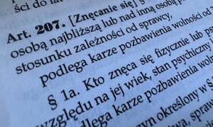 Zdjęcie przedstawia treść artykułu 207 Kodeksu karnego: §  1. Kto znęca się fizycznie lub psychicznie nad osobą najbliższą lub nad inną osobą pozostającą w stałym lub przemijającym stosunku zależności od sprawcy, podlega karze pozbawienia wolności od 3 miesięcy do lat 5.§  1a. Kto znęca się fizycznie lub psychicznie nad osobą nieporadną ze względu na jej wiek, stan psychiczny lub fizyczny, podlega karze pozbawienia wolności od 6 miesięcy do lat 8.§  2.  Jeżeli czyn określony w § 1 lub 1a połączony jest ze stosowaniem szczególnego okrucieństwa, sprawca podlega karze pozbawienia wolności od roku do lat 10. §  3. Jeżeli następstwem czynu określonego w § 1-2 jest targnięcie się pokrzywdzonego na własne życie, sprawca podlega karze pozbawienia wolności od lat 2 do 15.