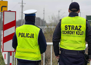 Policjant i strażnik patrzą w stronę torów