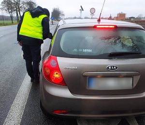 Policjant stojący przy samochodzie osoby kontrolowanej