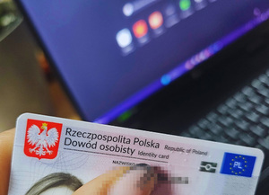 Zdjęcie przedstawia część dowodu osobistego, a w tle monitor komputera