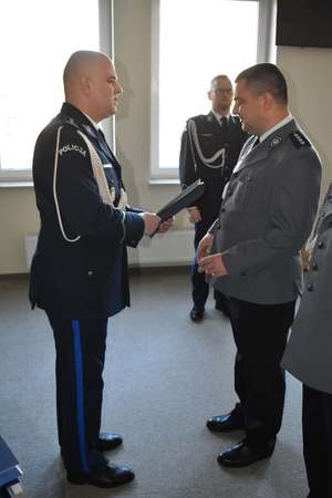 Policjant podaje teczkę policjantowi