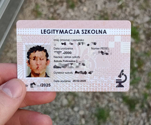 Dokument wyglądający jak legitymacja szkolna, trzymana w dłoni