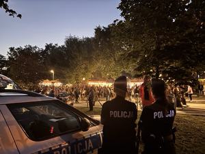 Policjanci stoją tyłem, a w tle miejsce imprezy