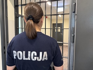 Policjantka patrzy w kierunku krat