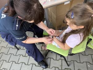Policjantka nakleja dziecku naklejkę na rękę