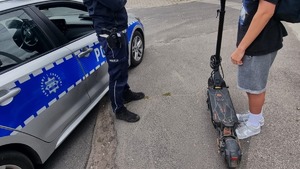 Policjant stoi obok chłopaka z hulajnogą