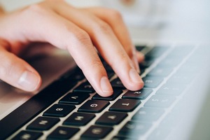 Męska dłoń na klawiaturze laptopa