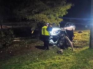 Policjant świeci latarką na rozbite auto