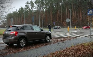 Samochód stojący przed przejściem na pasach po których idzie kobieta