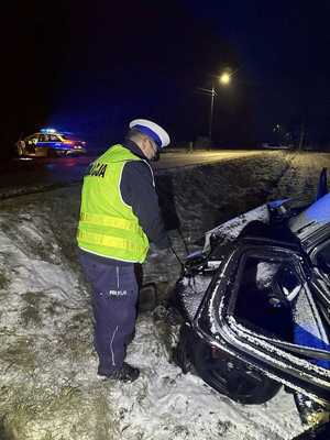 Policjant przy rozbitym samochodzie