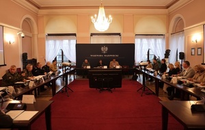 Zdjęcie przedstawiające salę ze stołami przy  których siedzi wiele osób