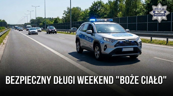 Radiowóz z włączonymi sygnałami jedzie ulicą, za nim inne auta. Poniżej napis bezpieczny długi weekend "Boże Ciało"