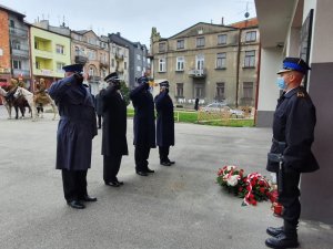 Policjant, przedstawiciel Wojska Polskiego i strażacy oddają honor przed tablicą strażaków z 1918 roku