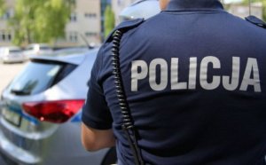 Grafika przedstawia policjanta stojącego tyłem z widocznym napisem Policja na jego plecach