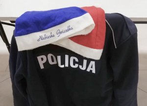 Tył polaru z napisem Policja i dwie czapki mikołaja w kolorze niebieskim i czerwonym