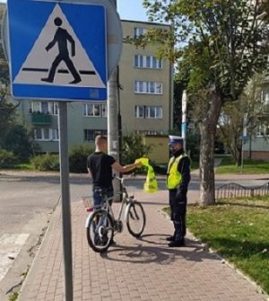 policjant wręcza kamizelkę odblaskową rowerzyście