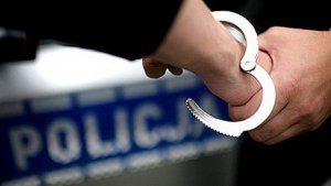 Policjant zakłada kajdanki na ręce zatrzymanego