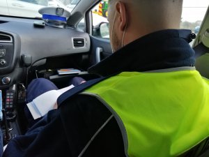 Policjant w radiowozie w trakcie sporządzania dokumentacji