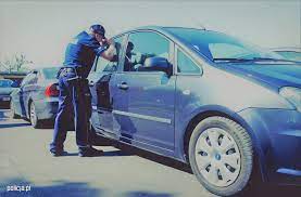 Policjant kontroluje wnętrze zaparkowanego auta.