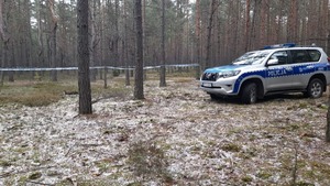 Policyjny radiowóz na miejscu zdarzenia w lesie.
