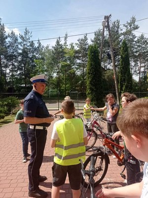 Dzieci z policjantem w trakcie egzaminu praktycznego.