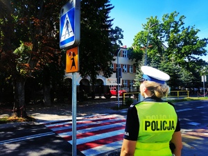 Policjantka sprawdza oznakowanie przy szkole.