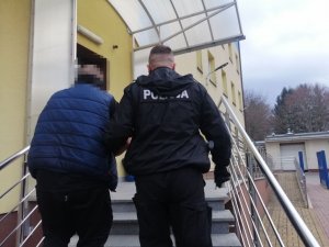 Policjant wprowadza zatrzymanego do KPP w Wyszkowie.