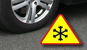 Koło samochodu oraz znak drogowy uwaga oblodzenie.