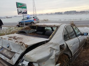Samochód w przydrożnym rowie. W tle radiowóz oraz zimowy krajobraz.