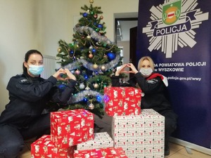 Policjantki oraz pracownica cywilna z prezentami. w tle policyjna choinka.