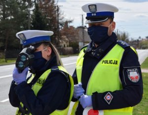 Na zdjęciu widać policjantów drogówki w trakcie pomiaru prędkości samochodu.