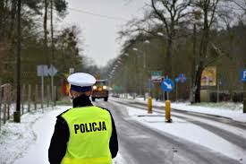 Na zdjęciu widać policjanta stojącego tyłem, w tle zimowy krajobraz.