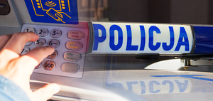 Po lewej stronie widzimy klawiaturę bankomatu a po prawej  sygnał świetlny z napisem Policja.