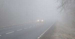 Zdjęcie przedstawia jadący samochód we mgle.
