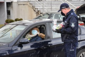 Dzień Kobiet z Policją. Na zdjęciu Policjanci wręczają uczestniczkom ruchu drogowego kwiaty oraz drobne upominki.