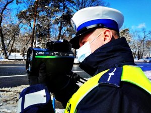 Policjant mierzący prędkość za pomocą miernika prędkości.