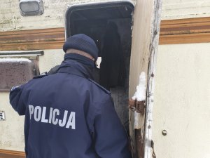 Policjant kontroluje  miejsca gdzie może przebywać osoba mogąca ulec wychłodzenia.