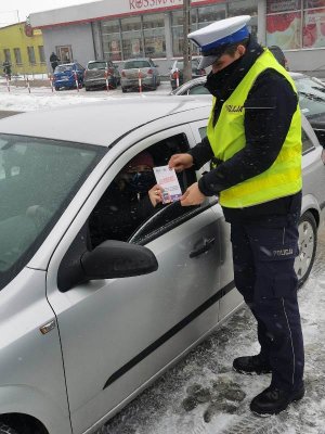 policjant ruchu drogowego przekazuje ulotkę promującą Krajową Mapę Zagrożeń Bezpieczeństwa