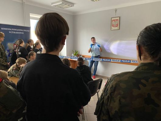 Dzień otwarty w KPP w Żyrardowie, na fotografii przedstawiony jest technik kryminalistyki który pokazuje uczestnikom ślady daktyloskopijne