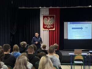 Policjant mówiący do siedzących w sali ludzi