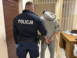 policjant prowadzi mężczyznę w kajdankach