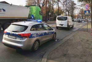 Miejsce wypadku na ul. 1 Maja  w Żyrardowie, gdzie potrącony został rowerzysta. Na zdjęciu widoczny radiowóz oraz pojazd biorący udział w potrąceniu, a także inne przejeżdżające auta