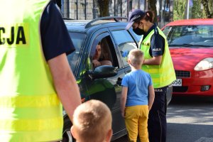 Policjanci wraz z dziećmi podchodzą do kierowców