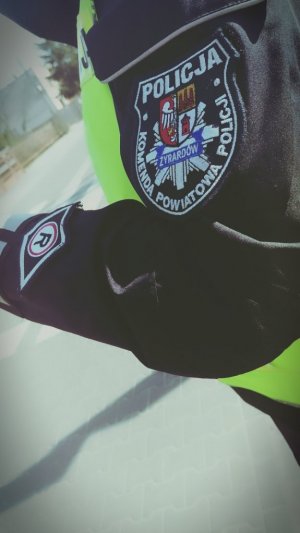 zdjęcie przedstawia rękę policjanta umundurowanego z przyczepioną naszywką z napisem Komenda Powiatowa Policji Żyrardów